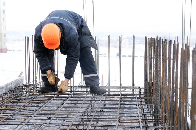 steel formwork - worker in workwear making reinforcement metal framework for concrete pouring