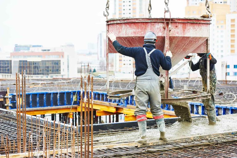 Reinforced concrete formwork - construction site worker during concrete pouring into formwork